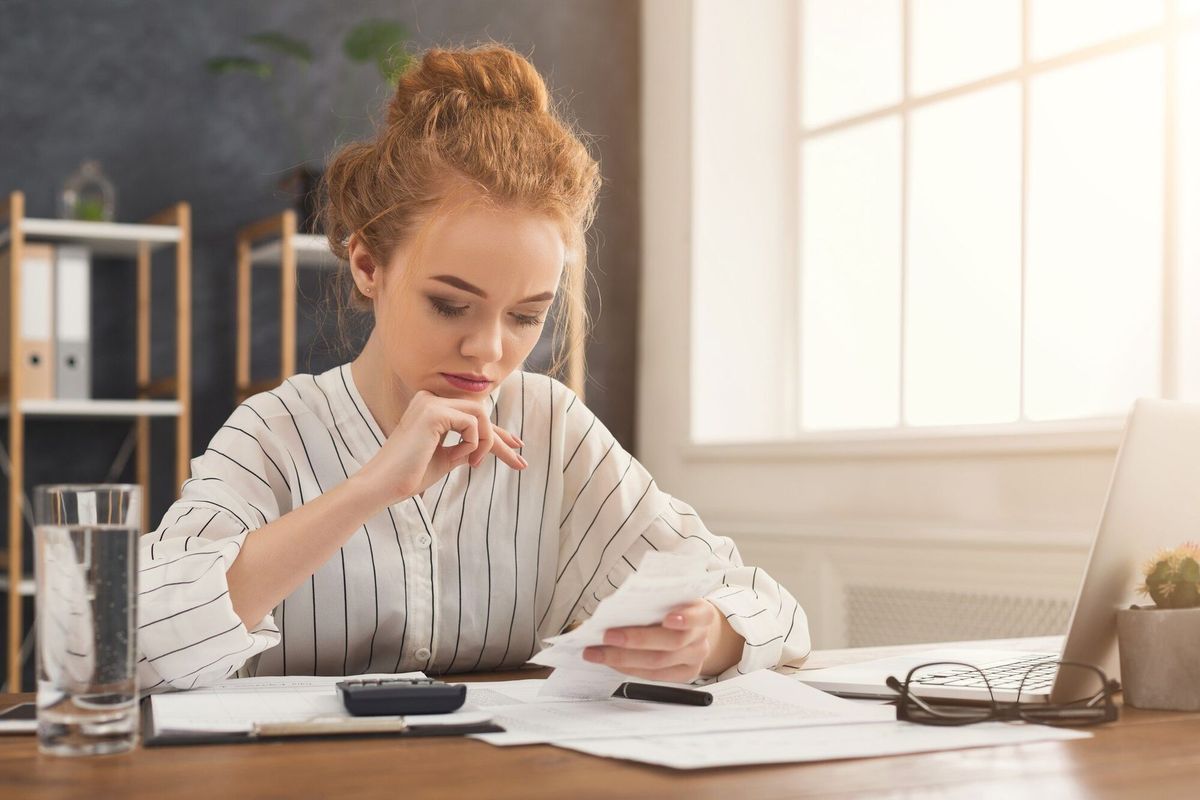 Serious business woman in office reading checks. Concentrated female manager working on marketing strategy at workplace